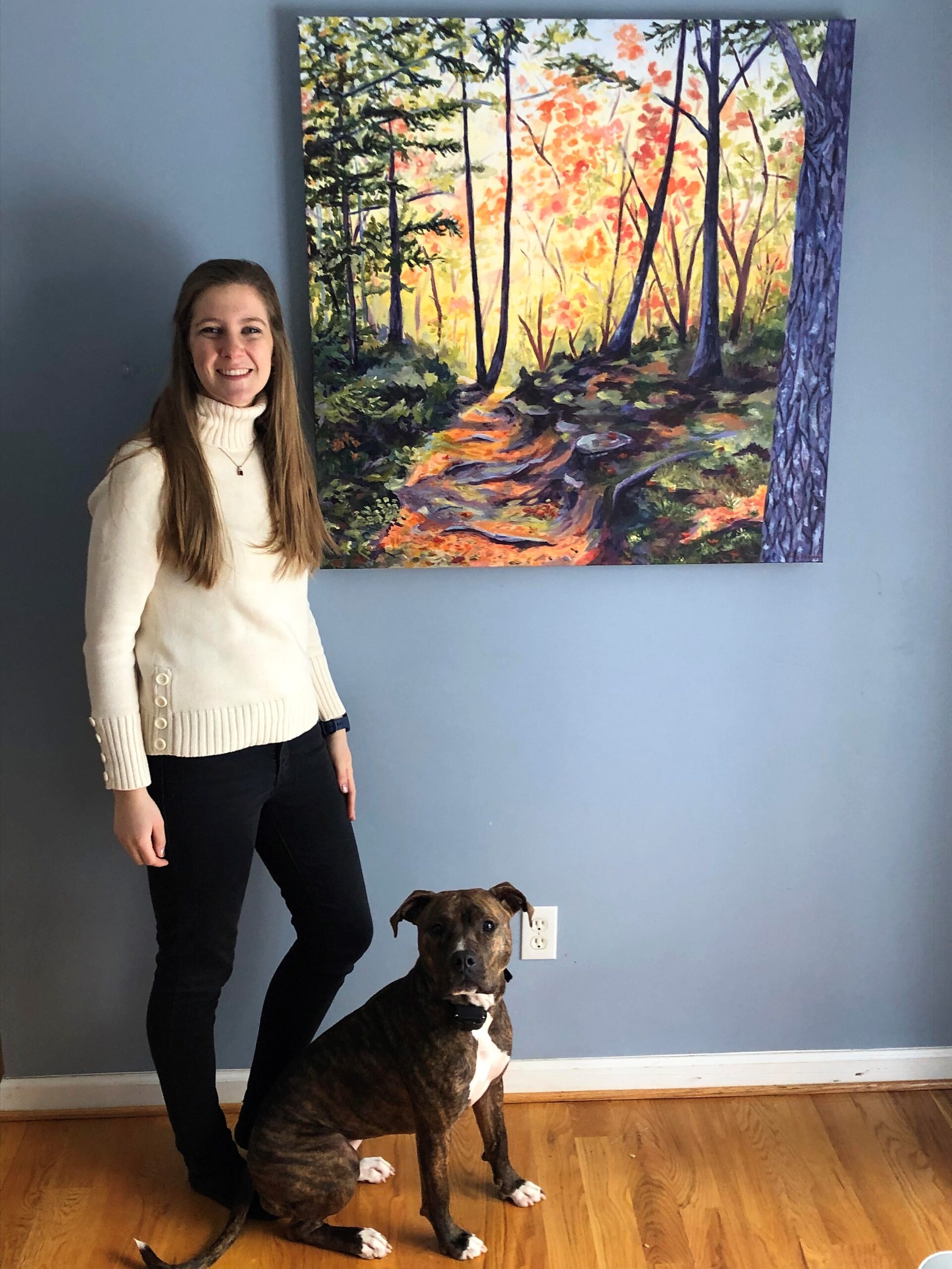 Mary Haapala in front of her painting with her dog